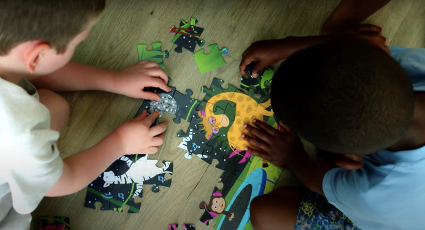 Load video: Children piecing together jigsaw puzzles on the kitchen floor